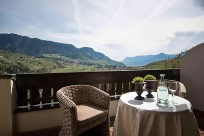 a table and chairs on a balcony with a view at Hotel Chalet Gravenstein in Tirolo