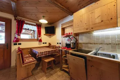 a kitchen with wooden cabinets and a sink and a table at Chalet Pian in Campitello di Fassa