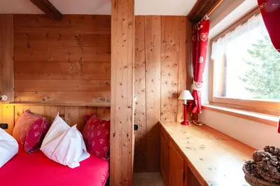 a bedroom with a red bed and a window at Chalet Pian in Campitello di Fassa