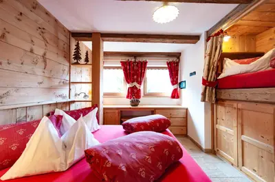 a bedroom with a red bed and two bunk beds at Chalet Pian in Campitello di Fassa
