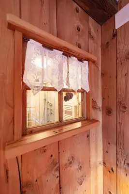 a window in a wooden wall with a curtain at Chalet Pian in Campitello di Fassa