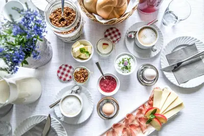 a white table with plates of food and cups of coffee at Rieplhof - Relaxing farm stay with breakfast and mountain view in Vipiteno