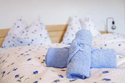 a blue teddy bear laying on a bed at Rieplhof - Relaxing farm stay with breakfast and mountain view in Vipiteno