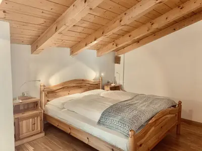 a bedroom with a wooden bed and wooden ceilings at Cesa Cascata in Canazei