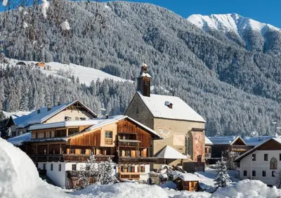 a church in the snow with mountains in the background at Luxury Larch Loft in Tesido