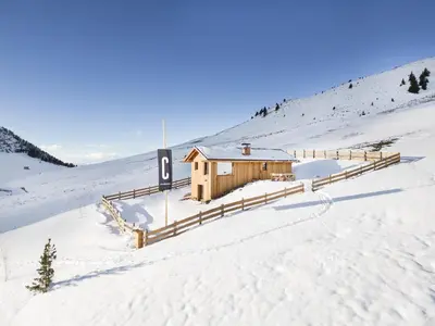 a wooden cabin in the snow on a snowy hill at Stay COOPER I DIAMANTIDI Lodge - Modern Mountain Chalet in the Dolomites in Obereggen