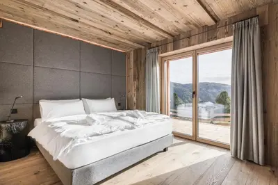a bedroom with a large bed and a large window at Stay COOPER I DIAMANTIDI Lodge - Modern Mountain Chalet in the Dolomites in Obereggen