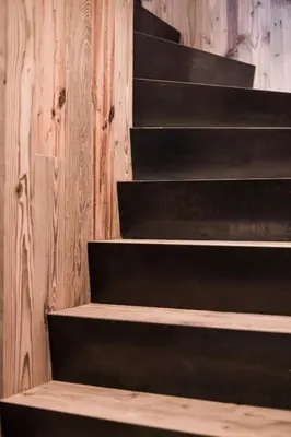a black staircase in a room with a wooden wall at Stay COOPER I DIAMANTIDI Lodge - Modern Mountain Chalet in the Dolomites in Obereggen
