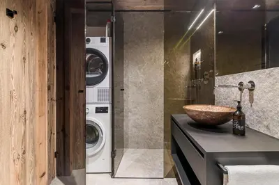 a bathroom with a sink and a washing machine at Stay COOPER I DIAMANTIDI Lodge - Modern Mountain Chalet in the Dolomites in Obereggen