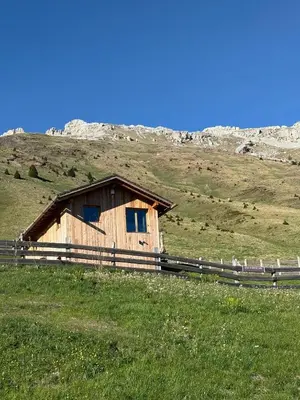 a wooden building on a hill in a field at Stay COOPER I DIAMANTIDI Lodge - Modern Mountain Chalet in the Dolomites in Obereggen