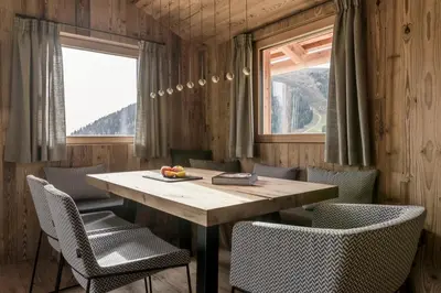 a dining room with a wooden table and chairs at Stay COOPER I DIAMANTIDI Lodge - Modern Mountain Chalet in the Dolomites in Obereggen