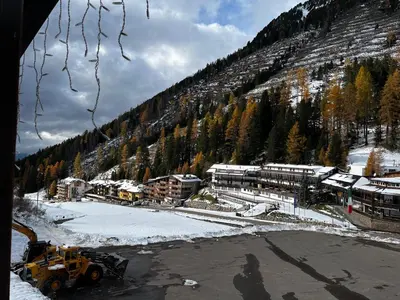 a snow covered mountain with a building and a bulldozer at Ski Lodge Pampeago in Tesero