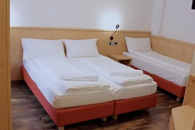 two beds in a room with white sheets at Ski Lodge Pampeago in Tesero