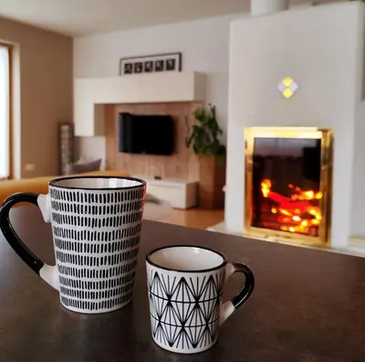 two coffee mugs sitting on a table with a fireplace at Apartment 66 - Modernes Apartment mit Balkon und Parkplatz in Toplage in Brixen in Bressanone