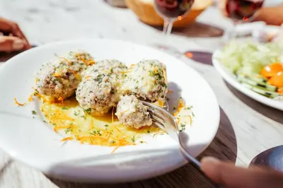 a plate of food with meatballs and a fork at Landhotel Gasthof Zum Löwen in Rodengo