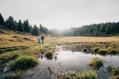 two people walking down a dirt road next to a pond at Landhotel Gasthof Zum Löwen in Rodengo