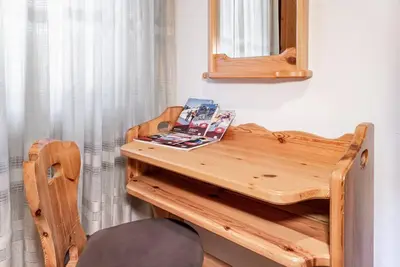 a wooden table with a mirror and a chair at Chalet Sassongher II in Corvara in Badia
