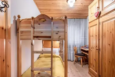 a bunk bed in a room with a desk and a desk at Chalet Sassongher II in Corvara in Badia