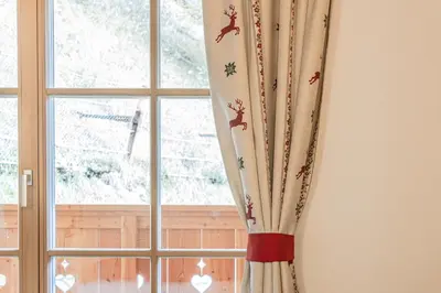a window with a curtain with deer on it at FARM CHALET JUSCIARA in Badia