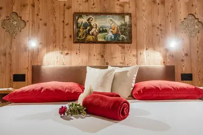 a bedroom with a bed with red pillows and a painting at FARM CHALET JUSCIARA in Badia