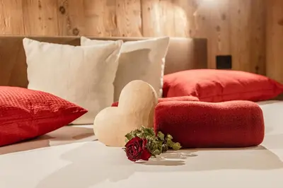 a bed with red pillows and a heart on it at FARM CHALET JUSCIARA in Badia