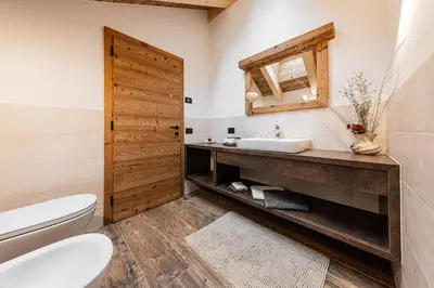 a bathroom with a sink and a toilet and a mirror at FARM CHALET JUSCIARA in Badia