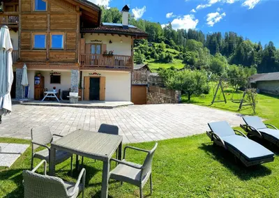 a patio with a table and chairs and a house at Casa Lazer in Tonadico