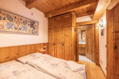 a bedroom with a bed and wooden walls at Casa Lacedel 2, on ski slopes in Cortina dʼAmpezzo