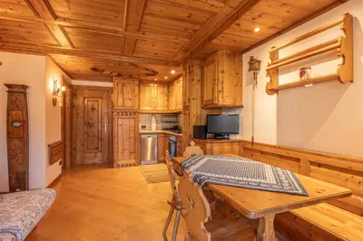 a dining room with a table and a kitchen at Casa Lacedel 2, on ski slopes in Cortina dʼAmpezzo