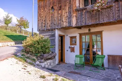 a house with two chairs sitting outside of it at Casa Lacedel 2, on ski slopes in Cortina dʼAmpezzo
