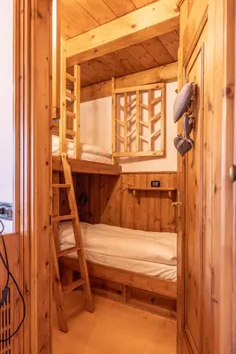 a bunk bed in a wooden room with a ladder at Casa Lacedel 2, on ski slopes in Cortina dʼAmpezzo