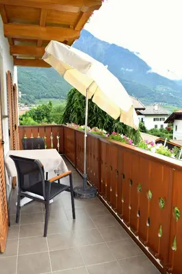 a patio with an umbrella and a table and chair at Tommelehof in Lagundo