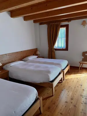 two beds in a room with wooden floors and a window at Agriturismo Busa dei Sbrase in San Cipriano