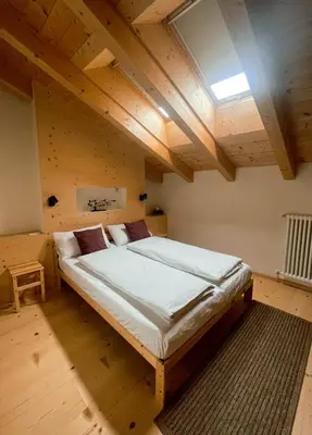 a large bed in a room with wooden ceilings at Maso Alpino con vista sulle Dolomiti in Mendola