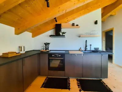 a kitchen with a black counter top and wooden cabinets at Maso Alpino con vista sulle Dolomiti in Mendola