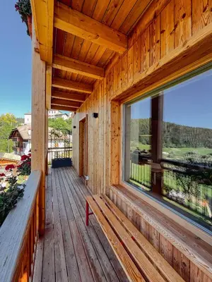 a porch of a wooden house with a large window at Maso Alpino con vista sulle Dolomiti in Mendola