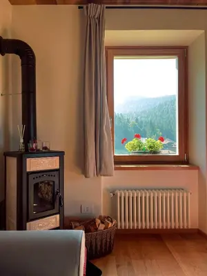 a bedroom with a fireplace and a window at Maso Alpino con vista sulle Dolomiti in Mendola