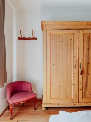 a red chair sitting next to a wooden cabinet at Maso Alpino con vista sulle Dolomiti in Mendola