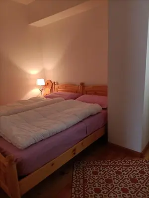 two beds in a bedroom with a lamp and a rug at La tua piccola casa a Pecol in Mareson