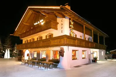 a building with benches in the snow at night at Hotel Val in Selva di Val Gardena