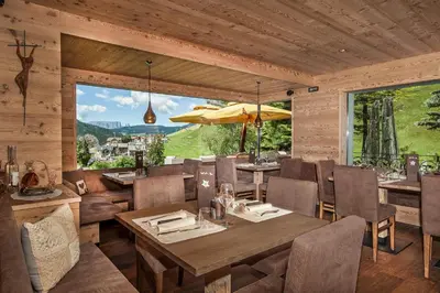 a dining room with a table and chairs and a large window at Hotel Val in Selva di Val Gardena