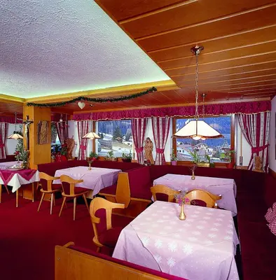 a restaurant with white tables and chairs and a window at Hotel Val in Selva di Val Gardena