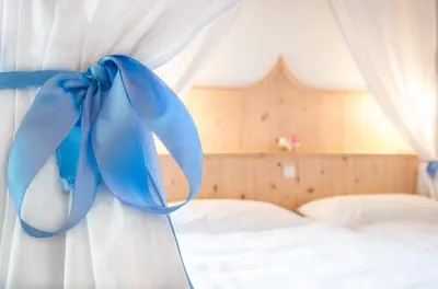 a blue bow on a white curtain in a bedroom at Garni Tschutscherhof in Laion