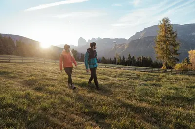 two people walking in a field with the sun setting at Garni Tschutscherhof in Laion