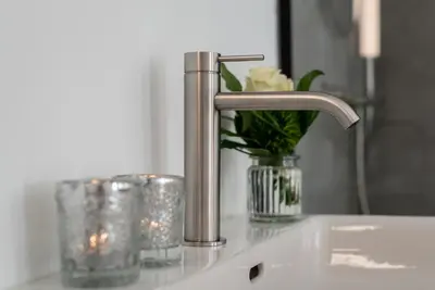 a bathroom sink with a faucet and a vase of flowers at KERAMIK Suites in Merano