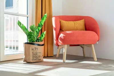 a red chair and a plant next to a window at KERAMIK Suites in Merano