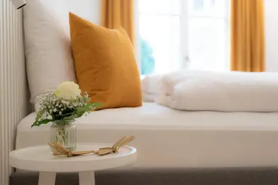 a vase of flowers on a table next to a bed at KERAMIK Suites in Merano