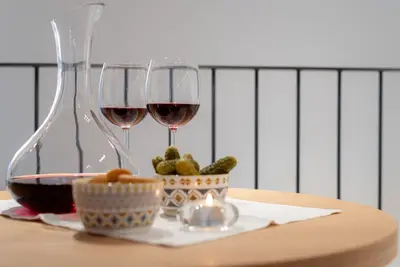 two glasses of wine and a bowl of pickles on a table at KERAMIK Suites in Merano