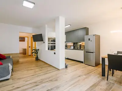a kitchen and living room with a table and a refrigerator at Apartment Enrosadira-9 by Interhome in Alba di Canazei