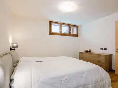a white bedroom with a bed and a window at Apartment Enrosadira-9 by Interhome in Alba di Canazei
